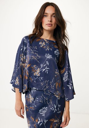 Blusa floreale blu navy con maniche a campana, caratterizzata da una texture setosa e un motivo botanico in marrone e azzurro chiaro.