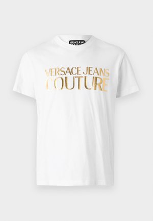 White cotton T-shirt featuring large gold foil text "VERSACE JEANS COUTURE" across the chest. Classic crew neck and short sleeves.