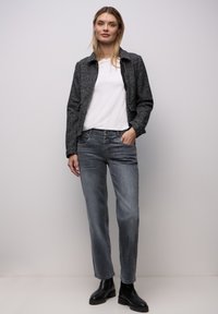 Szara kurtka o fakturze z przednimi kieszeniami, biała koszula i jasnoszare dżinsy. Całość dopełniają czarne botki za kostkę. Gładki, casualowy styl.