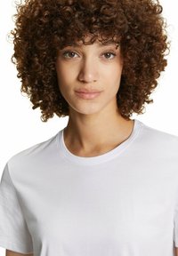 T-shirt bianco in cotone con scollo rotondo e maniche corte, che mostra una texture liscia e una forma aderente.