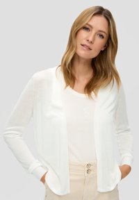 Witte open voorkant cardigan van lichtgewicht stof met lange mouwen, rib gebreide manchetten en een relaxte pasvorm, gelaagd over een lichtgekleurde blouse.