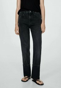 Black denim jeans with a straight leg design, featuring subtle whiskering, a high waist, and cuffed hems. Worn with flat sandals.