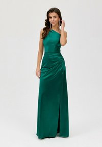 Zelené saténové večerní šaty s asymetrickým designem jednoho ramene, bočním nařasením a rozparkem na stehně, s hladkou, lesklou texturou.