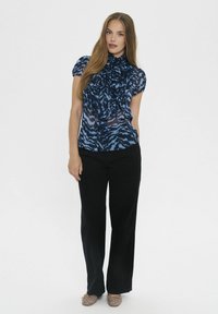 Tumši zils ziedu raksta blūze ar krokām un augstu apkakli, saskaņota ar melniem platiem biksēm un rotātām šļūtenēm. Tekstūrēta auduma, caurspīdīgas zonas.