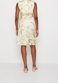 Bloemige jurk van een lichtgekleurde stof met roze en groene patronen, een mouwloze ontwerp en een licht uitlopende snit.