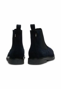 Botines de ante azul marino con paneles elásticos en los laterales, tiradores y suelas de goma negra texturizada. Diseño minimalista con una silueta elegante.