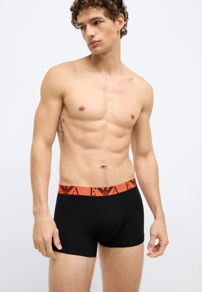Mutande boxer nere in cotone con elastico arancione in vita caratterizzato da un logo. Texture liscia, design aderente.