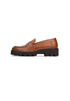 Mocasín de cuero marrón con detalles de tachuelas, que presenta una puntera redondeada y una suela gruesa negra. Textura suave y diseño minimalista.
