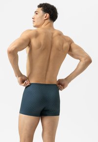 Shorts de bain pour homme en marine avec un motif géométrique. Fabriqués en matière extensible, ils présentent un design ajusté et une taille mi-haute.