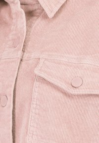 Roze corduroy jacket met een gestructureerd oppervlak, knopen aan de voorkant en twee borstzakken met ronde kleppen.