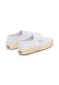 Sneaker bianche in tela con suola in gomma crema, punta rotonda, chiusura con lacci sul davanti e un piccolo logo sul tallone e sul lato superiore.