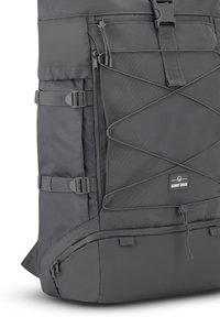 Mochila gris con un diseño texturizado, correas ajustables, bolsillos con cremallera y un logo prominente. Incluye un cordón bungee para almacenamiento adicional.