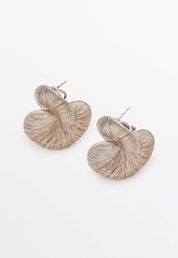 Orecchini metallici beige con un design a vortice e texture con rilievi. La chiusura è dotata di perno a scatto per un indosso sicuro.