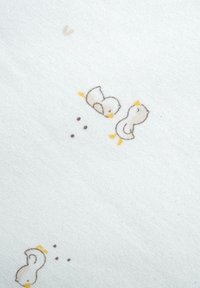 Tissu en coton avec un fond beige clair orné de canards en cartoon gris et jaune, entrecoupés de petits points marron.