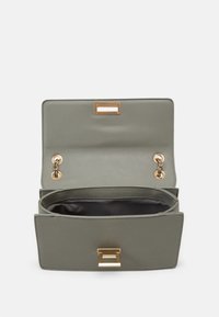 Zielona skórzana torebka z złotymi okuciami. Posiada sztywny kształt, zapięcie na klapę od góry oraz przestronne wnętrze z dwoma przegródkami.