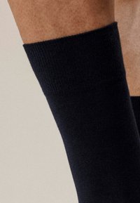 Granatowa skarpetka do kostki wykonana z miękkiego dzianiny z prążkowanym mankietem, podkreślająca gładką fakturę i dopasowany krój.