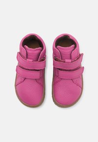 Roze leren schoenen met dubbele klittenbandsluiting, afgeronde vorm, textuurafwerking en een bruine rubberen zool. Geen extra versieringen.