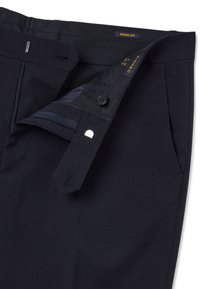 Pantalones azul marino con tejido texturizado, cierre de cremallera y botón, dos bolsillos laterales y una etiqueta que indica ajuste "REGULAR".