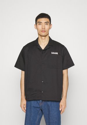 Fekete, rövid ujjú ing, könnyű anyagból készült, mellzsebbel és logóhímzéssel. Egyenes szabású, egyszerű gallérral és gombos záródással.