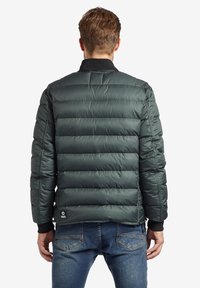 Pružná bombera v tmavě zelené barvě s manžetami a límcem s žebrováním, s horizontálním prošíváním a logem na dolním lemu.