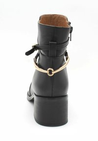 Czarne skórzane botki za kostkę z masywnym obcasem, z akcentem w kolorze złotym oraz zamkiem błyskawicznym z boku, wykończone teksturowaną podszewką wewnętrzną.