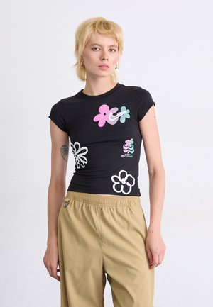 Camiseta negra de manga corta con estampado de flores en tonos pastel de color rosa, verde y blanco; diseño ajustado con cuello redondo.