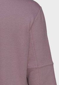 Lichtpaarse trui met textuur in de stof, zichtbare naden en een ronde halslijn. Het ontwerp is casual en eenvoudig.