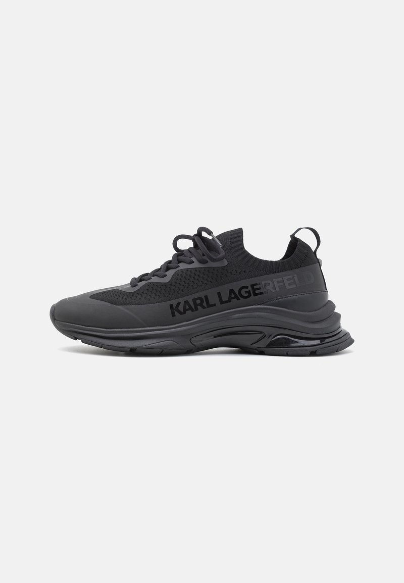 Baskets de sport noires avec empeigne en maille, semelle épaisse, languette au talon et marquage "KARL LAGERFELD" sur le côté.