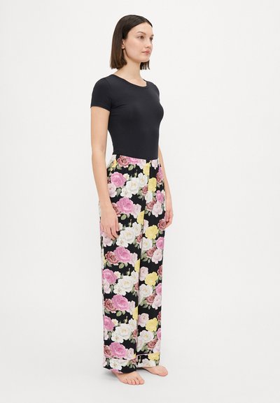 Svart t-skjorte med korte ermer sammen med løstsittende pysjamasbukser med blomsterdesign som har rosa, hvite og gule roser mot en svart bakgrunn.