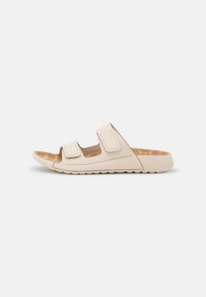 Lys beige slidesandal med to velcro-stropper, struktureret sål og en struktureret gummisål for godt greb. Minimalistisk design.