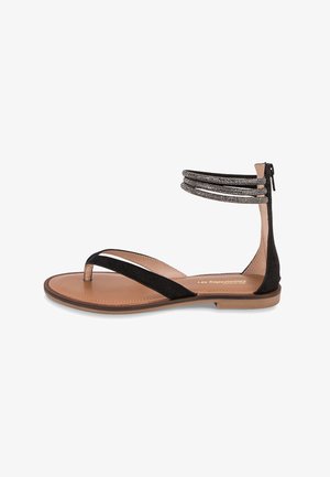 Zwarte suède sandalen met een teenlus, dunne bandjes en een decoratieve enkelband met kralen. De zool is lichtbruin met een gladde afwerking.