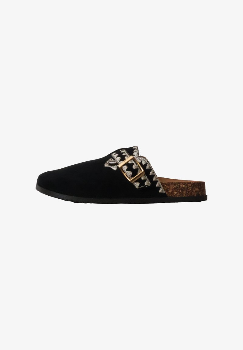 Sabot noir à enfiler avec semelle en liège, couture blanche en zigzag et boucle dorée réglable sur le côté.