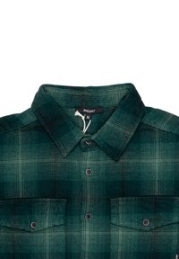 Camicia in flanella a quadri verdi con colletto a bottoni, due tasche sul petto e bottoni neri. Presenta un tessuto testurizzato e un'etichetta vicino al colletto.