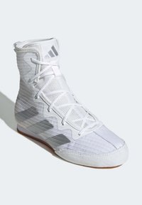 Valkoiset urheilukengät, joissa on korkeavartinen malli, teksturoitu kangas, nauhakiinnitys ja kumipohja, harmailla korostusraidoilla sivulla.