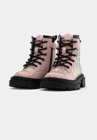 Botas de combate brillantes de color rosa con acentos negros, parte superior texturizada, suela resistente y gráfico de sirena en el costado. Cierre de cordones y cremallera lateral.