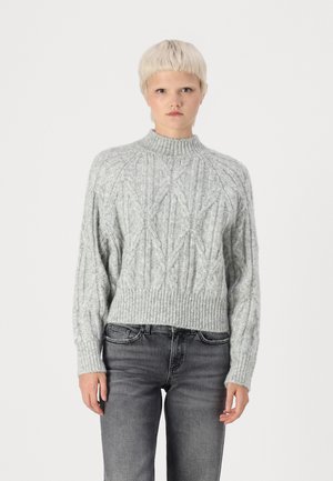 Light gray cropped sweater in textured knit with a diamond pattern and ribbed collar and hem. Paired with gray jeans.
