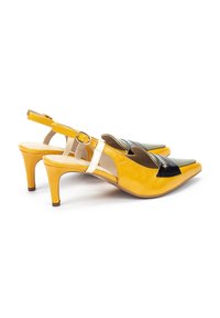 Escarpins jaunes à talons slingback avec un bout pointu, présentant un panneau d'accent noir et une bride blanche à boucle. Texture en cuir lisse.
