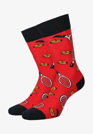 Czerwone skarpetki z czarnymi mankietami, z wzorem rakiet tenisowych i żółtymi piłkami tenisowymi. Materiał z mieszanki bawełny, gładka tekstura.