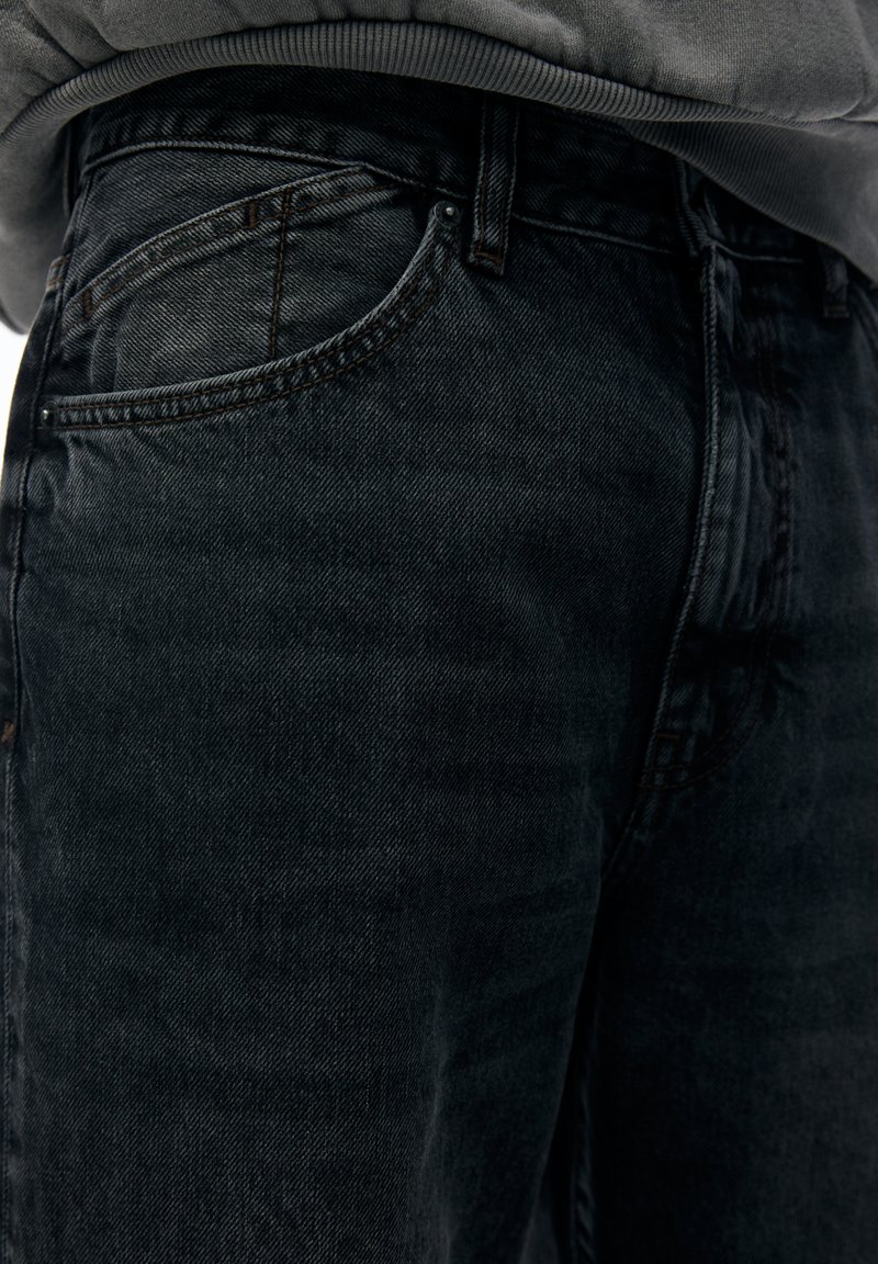 Jeans in denim scuro con un design aderente, caratterizzati da una classica stile a cinque tasche, leggere sfumature e dettagli di cucitura a contrasto.