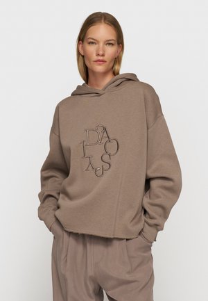 Felpa cropped marrone con cappuccio regolabile e vestibilità oversize. Presenta un logo geometrico cucito in una tonalità più scura. Tessuto morbido.