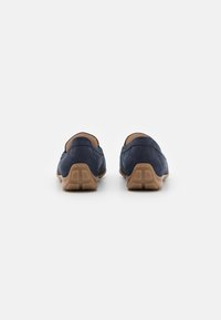 Navyblaue Wildleder-Slipper mit abgerundetem Rücken, beige Gummisohle und minimalen Nähakzenten. Glatte Textur und lässiges Design.
