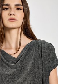 Metallisch graues, drapiertes Top mit kurzen Ärmeln. Weiche Textur und Wasserfall-Ausschnitt, mit sanften Falten und lockerer Passform.