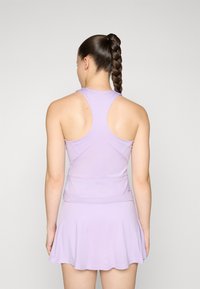 Lila Sportbekleidung, bestehend aus einem Racerback-Trägershirt und einem schwingenden Skort. Das Material wirkt dehnbar mit einer glatten Textur und ohne sichtbare Muster.