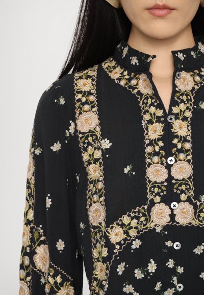 Blusa in tessuto nero con intricato ricamo floreale in rosa e bianco, colletto alto, chiusura con bottoni e dettagli texturizzati.