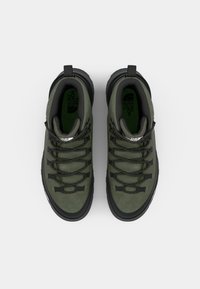 Green suede hiking shoes with black accents, featuring a rugged sole, reinforced eyelets, and grey laces. The inner lining is a dark green.