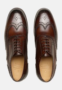 Braune Lederbusinessschuhe mit Broguemuster, ausgestattet mit durchbrochenen Details, abgerundetem Zehenbereich und Schnürung. Glatte Oberfläche und robuste Sohle.