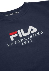 Sudadera azul marino con cuello acanalado, con logo y texto bordados de FILA en blanco y rojo, y la inscripción "ESTABLISHED 1911" en blanco debajo del logo.