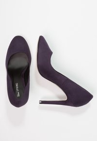 Escarpins en suede violet avec un bout pointu, un talon aiguille fin et une doublure intérieure lisse. Présente un design minimaliste sans embellissements.