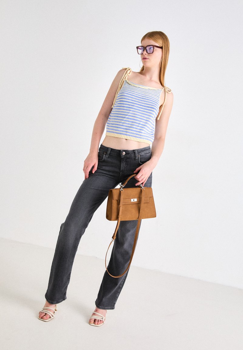 Dzianinowy top do pępka w niebiesko-kremowe paski z zawiązywaniem na ramionach, zestawiony z ciemnoszarymi spodniami wysokiego stanu i małą brązową torebką.