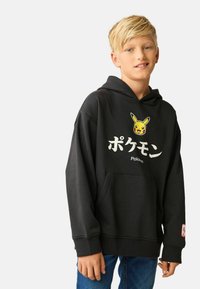 Black hoodie featuring a Pikachu graphic and Japanese text. Material is soft, with a front pocket and ribbed cuffs. Casual design.